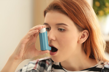 Young woman using inhaler for asthma and respiratory diseases at home