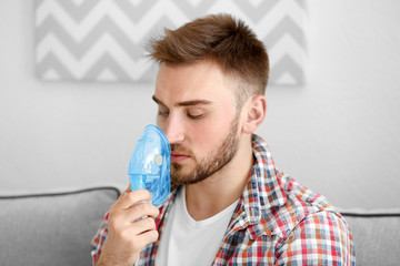 Young man using nebulizer for asthma and respiratory diseases at home