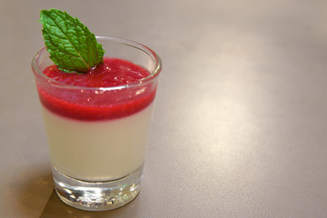 delicious raspberry panna cotta in clear glass on the wood table and warm white light for sweet...
