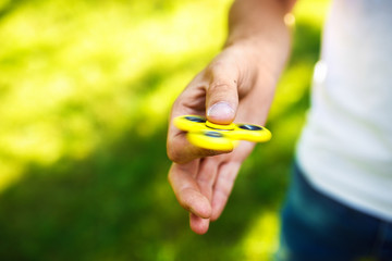 Young boy playing with a fidget spinners in the park. stress relieving toy. Sunny summer day. laugh...