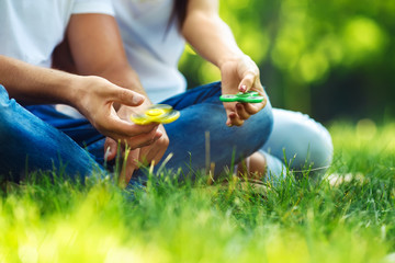 Young girl and boy playing with a fidget spinners in the park. stress relieving toy. Sunny summer...