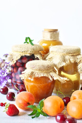 Various jams and compotes with fresh fruits on white wood