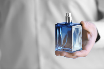 Young man with bottle of perfume, closeup