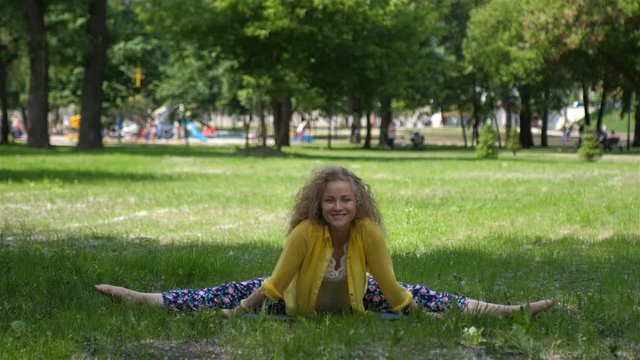 Pregnant woman relaxes and does yoga in a park on the grass HD