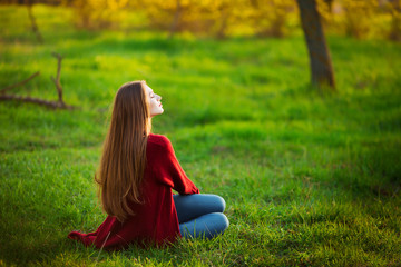 Portrait of happy sporty woman relaxing in park on green meadow. Joyful female model breathing fresh air outdoors. Healthy active lifestyle concept.