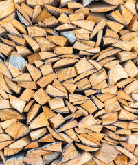 Background of dry chopped firewood logs stacked up on top of each other in a pile in winter