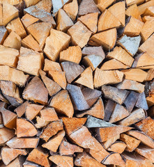 Background of dry chopped firewood logs stacked up on top of each other in a pile in winter