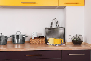 Composition with mugs, bag and plant on counter in kitchen