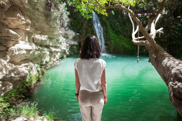 Fototapeta premium Back view of young woman enjoy waterfall on beautiful lake