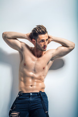Naklejka premium Sexy muscular shirtless man posing against white wall