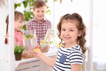 Obraz premium Cute little girl buying lemonade from kids at stand