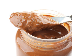 Creamy peanut butter on knife and jar on white background, closeup