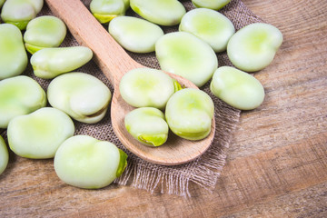 Green fresh broad beans on old wooden table.