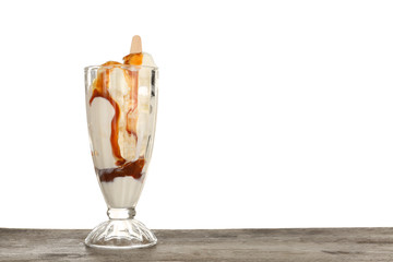 Dessert glass with vanilla ice cream and caramel sauce on table