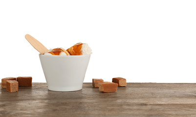 Bowl with vanilla ice cream and caramel sauce on table
