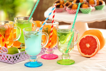 Glasses with different kinds of lemonade on table outdoor