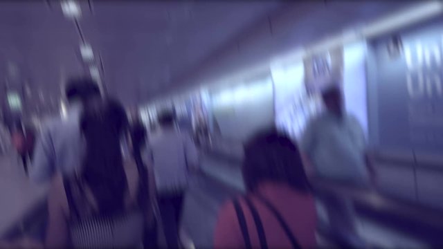 Blurred silhouettes of people moving on flat escalators at the airport