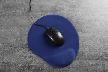 Blank mat and computer mouse on textured background
