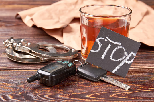 Handcuffs, car keys, whisky, paper. Driving keys, metal handcuffs, message stop, whiskey. Hard judgment for road accident.