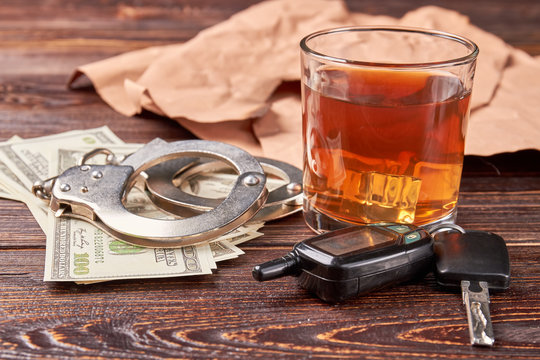 Whiskey, handcuffs, car key, money. Booze driving concept.