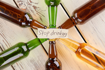 Do not be loser, stop drinking. Set of colorful bottles of alcoholic beverages, wooden table.