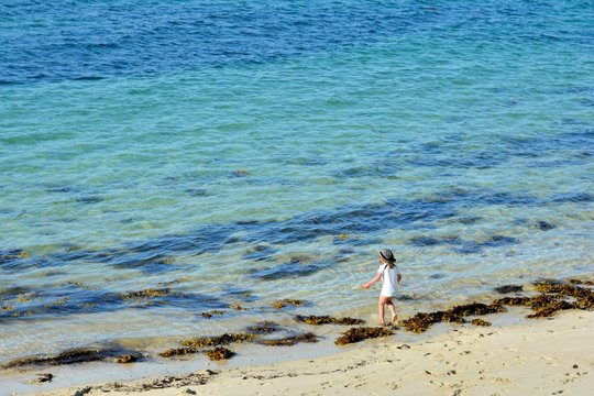 Une fillette va chercher de l'eau de mer sur une plage en Bretagne