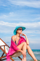 Woman sitting on a deck chair at the beach
