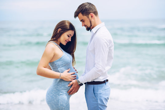 Loving couple touching with love and care a pregnant belly with their hands.