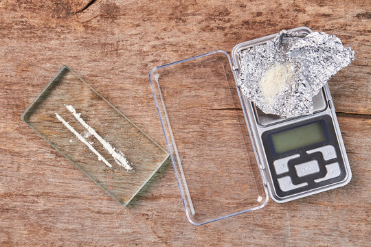 Narcotics, digital scales, wooden background. White powder, glass, scale, foil, old wooden floor.