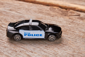 Toy Police Car on a Wooden Floor. Black police car with alarm on blurred background.