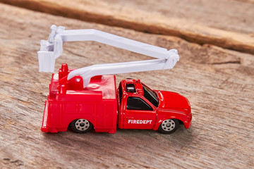 Red toy fire truck, wooden background. Model of fire lorry, old wooden floor.