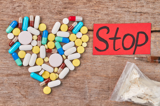 Stop use drugs how to. Pills shaped heart, narcotics, message, wooden background.