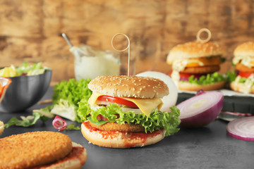 Composition with tasty homemade burger and vegetables on table