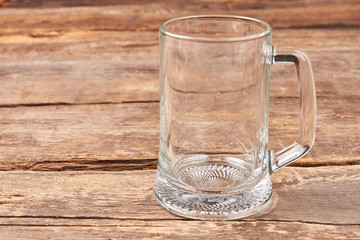 Empty glass mug, wooden table. Transparent glass for beer on wooden retro board.