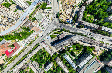 Fototapeta premium Aerial city view with crossroads and roads, houses, buildings, parks and parking lots, bridges. Helicopter drone shot. Wide Panoramic image.