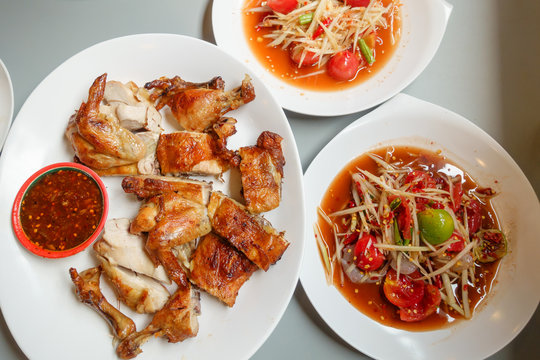 grilled chicken with thai sauce and papaya salad or spicy salad of thailand on white plate