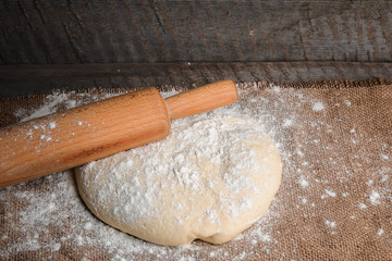 Ball of dough and rolling pin on rustic background