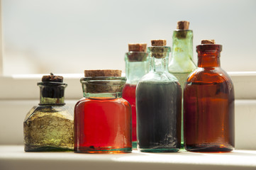 Many antique glass bottles with colored liquids close up. For the pharmacy, oil, cosmetics.