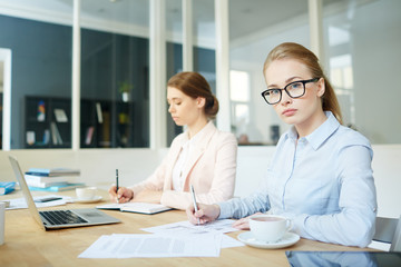 Serious student looking at camera by desk