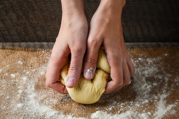 Hands prepare dough on a dark background