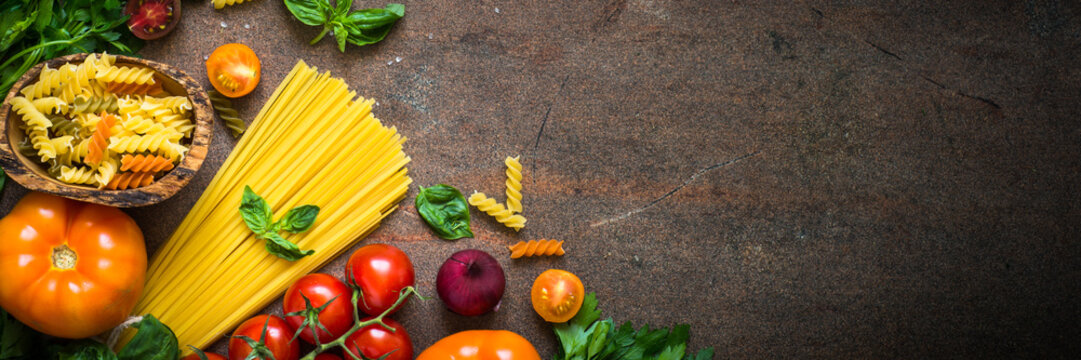 Italian food background. Pasta spaghetti, tomatoes, basil. Long banner format.