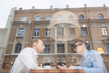 Two young co-workers having talk in urban cafe