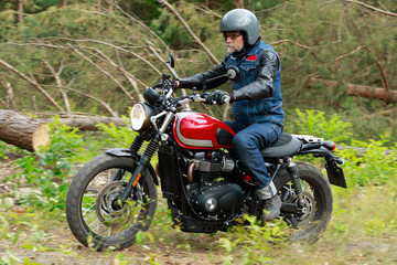 Man in grey helmet riding the red motorcycle in the forest