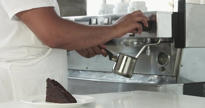 barista prepare milk with cffee machine in backround