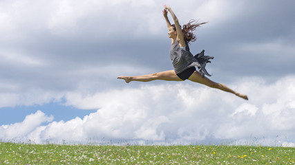Young dancer in  mid air doing the splits outdoors