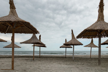 Straw beach umbrellas at seaside, empty beach, cloudy day, in Mamaia, Romania, the Black Sea
