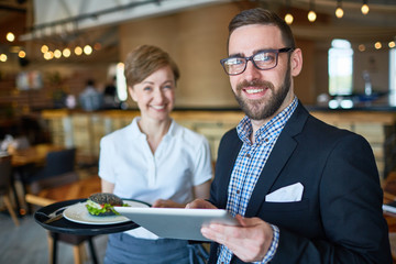 Elegant trader with touchpad and waitress with sandwich on tray