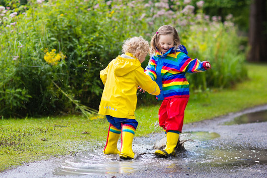 Kids Play In Rain And Puddle In Autumn