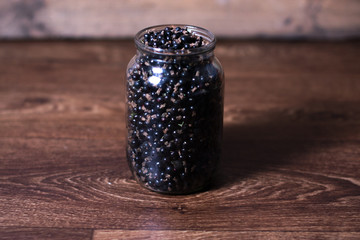Fototapeta na wymiar Black currant in a glass jar on a wooden background.