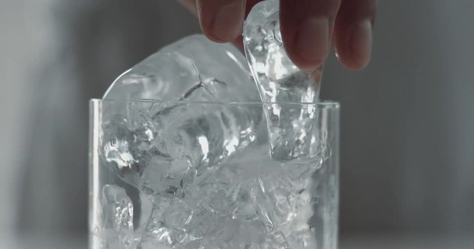 barist puuts an ice cube in glass